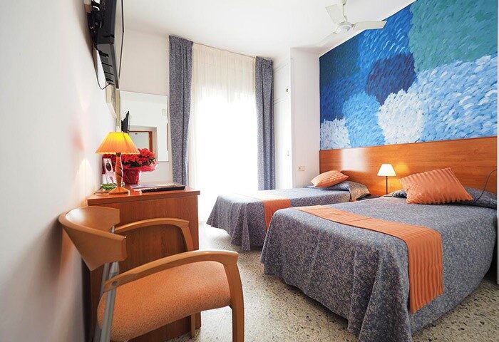 Hotel Montserrat gay-friendly room with two beds, colorful wall art, and modern amenities. Comfortable lodging for gay men travelers.