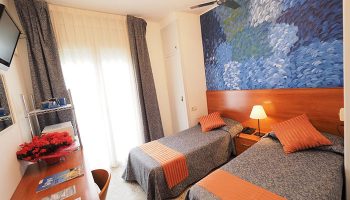 Hotel Montserrat gay-friendly hotel room with twin beds, desk, and blue mural. Comfortable lodging for gay travelers seeking a welcoming stay.