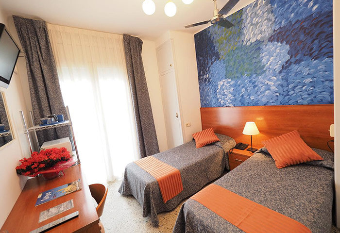 Hotel Montserrat gay-friendly hotel room with twin beds, desk, and blue mural. Comfortable lodging for gay travelers seeking a welcoming stay.