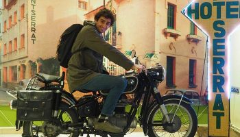 Gay traveler on a motorcycle at Hotel Montserrat, a gay-friendly hotel. Vintage bike and travel vibes for gay men's holiday.