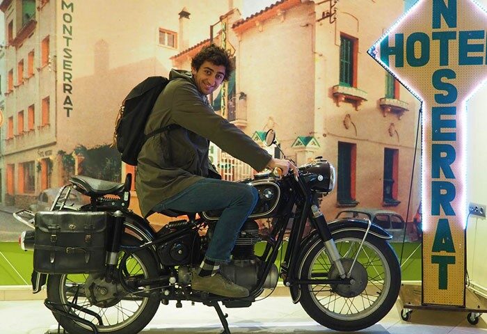 Gay traveler on a motorcycle at Hotel Montserrat, a gay-friendly hotel. Vintage bike and travel vibes for gay men's holiday.