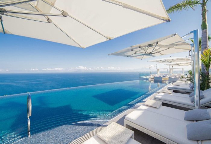 Hotel Mousai Cancun adults-only all-inclusive gay-friendly resort. Infinity pool, ocean view, lounge chairs, and umbrellas for a luxurious getaway.