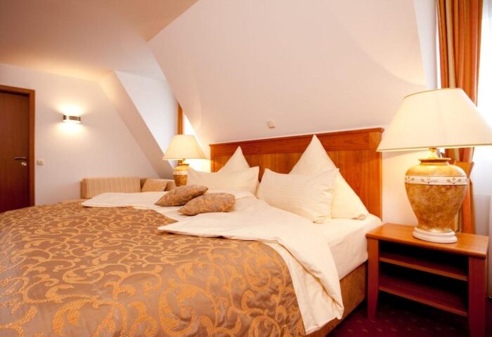 Hotel Müller Munich gay-friendly room. Bedroom with double bed, patterned brown cover, bedside table, and lamps. Comfortable, inviting space.