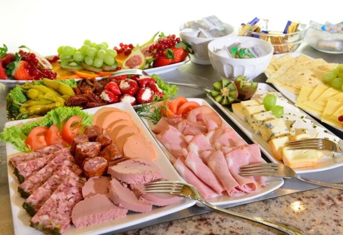 Hotel Müller Munich's gay-friendly breakfast buffet. Meats, cheeses, and fruits are displayed. A delicious spread for gay travelers.
