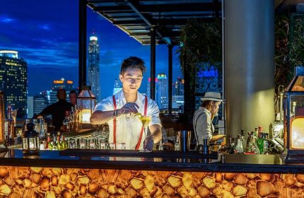 Gay-Friendly Hotel Muse Bangkok Langsuan: Bartender at rooftop bar. Bangkok skyline view. MGallery Collection hotel for gay travelers.