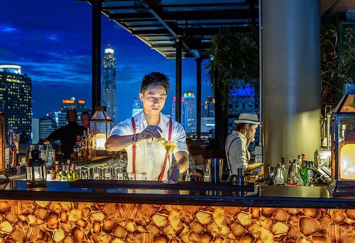 Gay-Friendly Hotel Muse Bangkok Langsuan: Bartender at rooftop bar. Bangkok skyline view. MGallery Collection hotel for gay travelers.