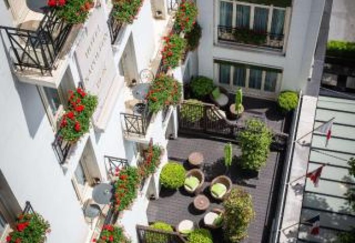 Hotel Napoleon, a gay-friendly & pet-friendly hotel. Balconies with flowers, and a rooftop terrace with seating, plants, and French flags.