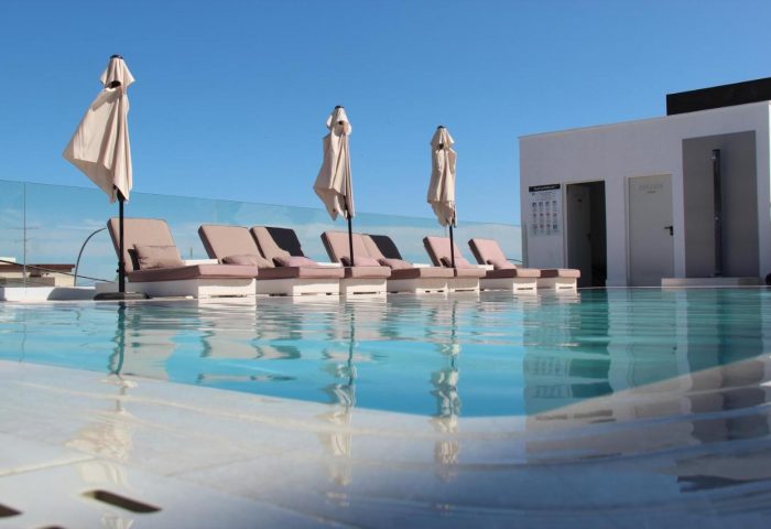 Hotel Natursun pool view. Gay-friendly hotel with sunbeds and parasols reflected in the water. A perfect spot for relaxation and gay travel.