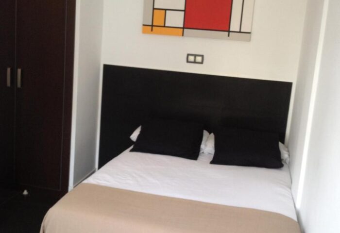 Hotel Natursun's gay-friendly room. Double bed with black headboard, colorful Mondrian-style art, and dark wardrobe. Modern design.