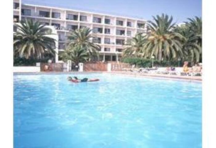 Hotel Nautico Ebeso's pool area. Gay-friendly hotel with palm trees, blue water, and guests relaxing. A great spot for gay men's travel in Ibiza.