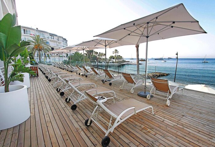 Hotel Nautico Ebeso gay-friendly hotel deck. Sun loungers and umbrellas on a wooden terrace overlooking the sea. Gay travel in Ibiza.