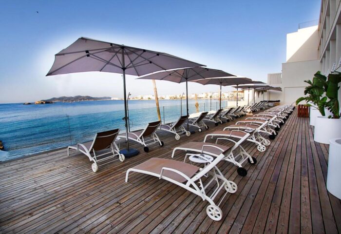 Hotel Nautico Ebeso's gay-friendly vibe: deck chairs & umbrellas overlook the sea. A perfect spot for gay men's travel in Ibiza.