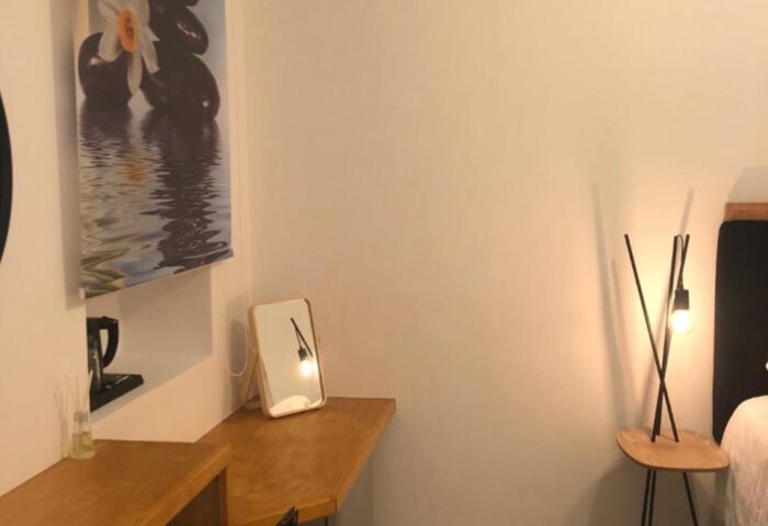 Hotel Nazos Mykonos Town room detail. Gay-friendly hotel room features desk, chair, lamp, and zen-themed art. Modern, clean design.