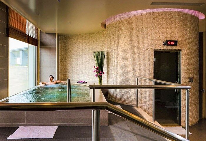 Gay-Friendly Hotel Nikko Saigon: Man relaxing in a jacuzzi at the hotel spa. Sauna entrance visible. Luxury travel for gay men.