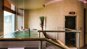 Gay-Friendly Hotel Nikko Saigon: Man relaxing in a jacuzzi at the hotel spa. Sauna entrance visible. Luxury travel for gay men.