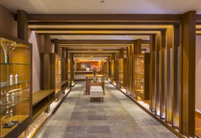 Hotel Nikko Saigon's interior. This gay-friendly hotel features a hallway with wooden beams, display cases, stone floors, and a reception desk.