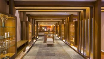Hotel Nikko Saigon's interior. This gay-friendly hotel features a hallway with wooden beams, display cases, stone floors, and a reception desk.