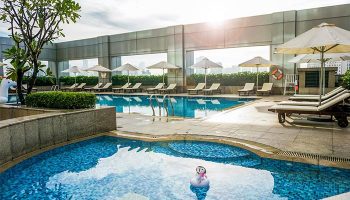 Hotel Nikko Saigon's rooftop pool. This gay-friendly hotel in Saigon offers a luxurious experience with sun loungers and city views. Relax in style.