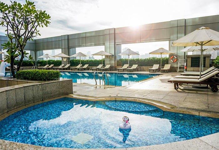 Hotel Nikko Saigon's rooftop pool. This gay-friendly hotel in Saigon offers a luxurious experience with sun loungers and city views. Relax in style.