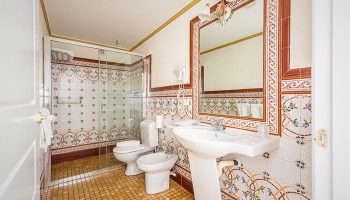 Hotel Noucentista gay-friendly bathroom featuring a shower, toilet, bidet, and sink with decorative tilework. Ideal for gay travel.