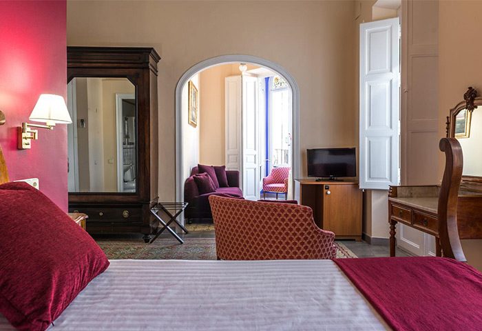 Hotel Noucentista gay-friendly room. Bedroom with living area, wardrobe, desk, TV, and balcony. A comfortable stay for gay travelers.