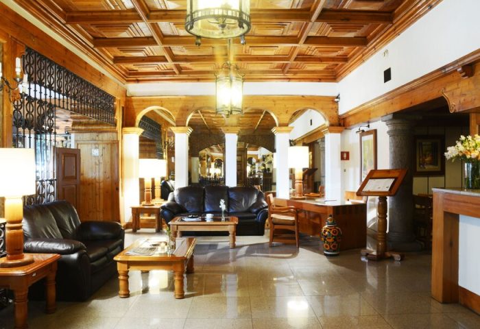 Hotel PF's lobby. Elegant interior with wooden ceiling, leather sofas, and lamps. A gay-friendly hotel offering a welcoming space.
