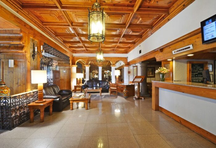 Hotel PF's lobby: a gay-friendly hotel featuring a wood-paneled ceiling, leather sofas, and a reception desk. A cozy and welcoming space.