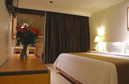 Hotel PF room interior. Gay-friendly Hotel PF features a bed, roses, desk, and curtains. Ideal for gay men's travel, offering comfort and style.