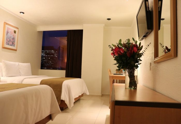 Hotel PF gay-friendly room with two beds, night cityscape view, flowers, and TV. A comfortable stay for gay travelers.