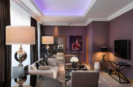 Hotel Palace Berlin's gay-friendly, pet-friendly room. Elegant decor, purple walls, stylish lamps, and modern furniture create a luxurious ambiance.