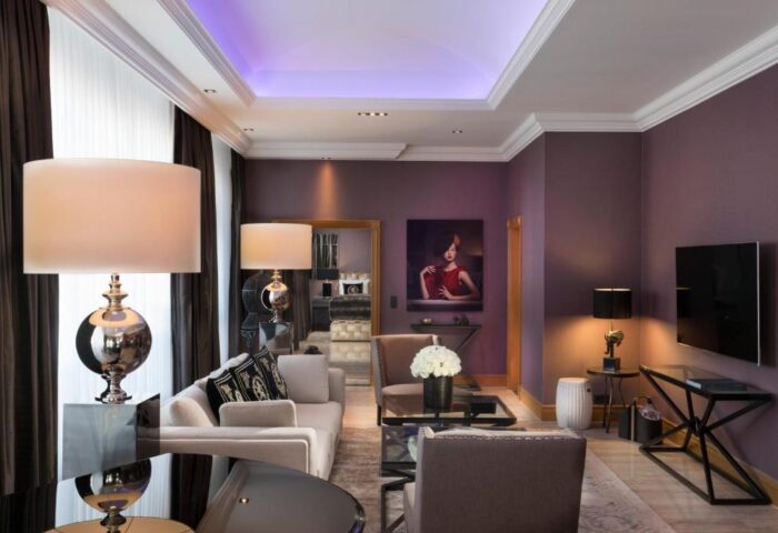 Hotel Palace Berlin's gay-friendly, pet-friendly room. Elegant decor, purple walls, stylish lamps, and modern furniture create a luxurious ambiance.