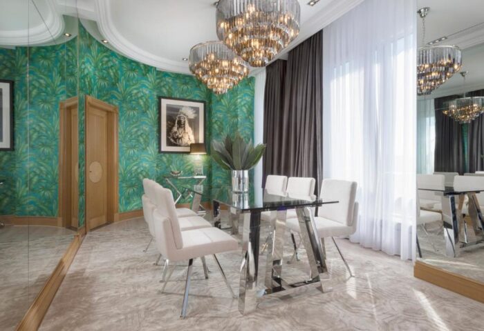 Dining room at Hotel Palace Berlin, a gay-friendly and pet-friendly hotel. Features tropical wallpaper, mirrored walls, and modern chandeliers.