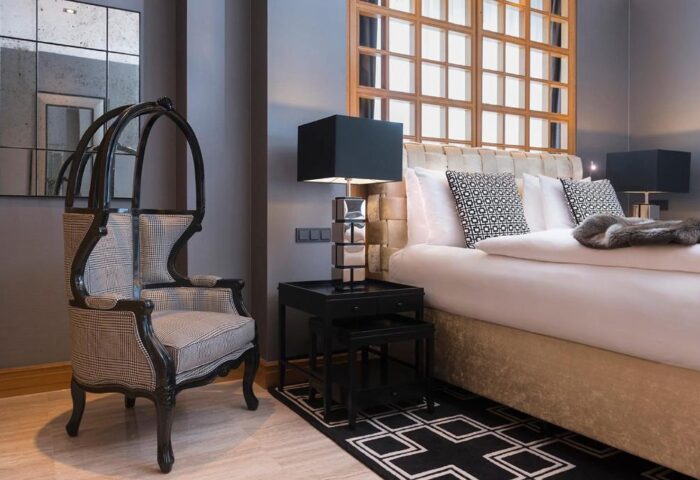 Hotel Palace Berlin gay-friendly room. A pet-friendly hotel, chair, bed, and lamp are visible. Stylish, comfortable lodging.
