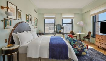 Hotel Per La, Autograph Collection room. Gay-friendly hotel bedroom with bed, blue throw, floral sofa, and city view. Upscale lodging.