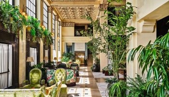 Hotel Per La, Autograph Collection's lavish lobby. Gay-friendly hotel with ornate ceilings, lush plants, and stylish seating. A luxury travel experience.