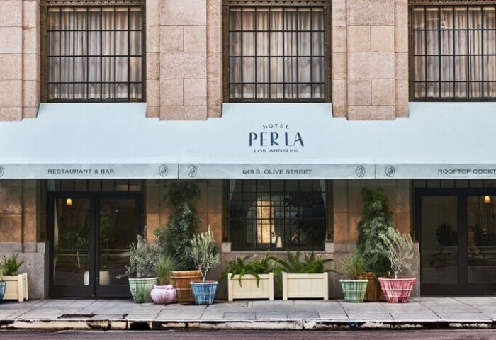 Hotel Per La, Autograph Collection facade. Gay-friendly hotel in Los Angeles with restaurant, bar, and rooftop cocktails. Plants decorate entrance.