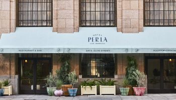 Hotel Per La, Autograph Collection facade. Gay-friendly hotel in Los Angeles with restaurant, bar, and rooftop cocktails. Plants decorate entrance.