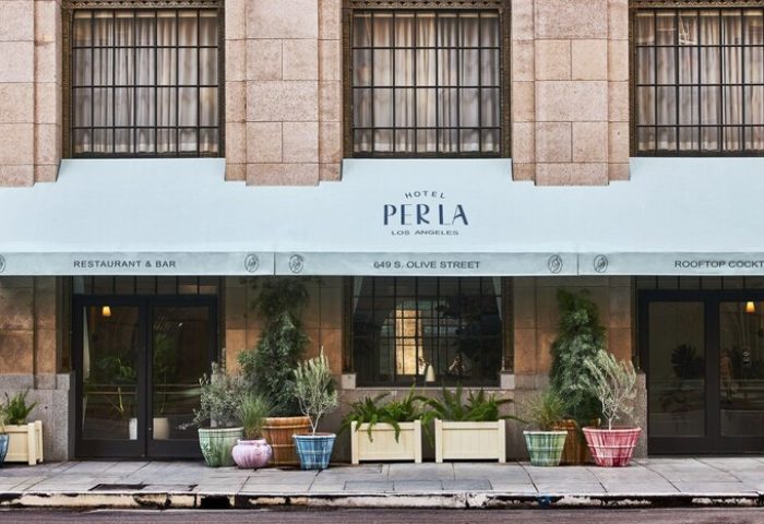 Hotel Per La, Autograph Collection facade. Gay-friendly hotel in Los Angeles with restaurant, bar, and rooftop cocktails. Plants decorate entrance.