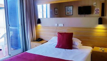 Hotel Piccadilly Sitges gay-friendly room. Balcony view, double bed with red accents, TV, and modern decor. A relaxing stay in Sitges.