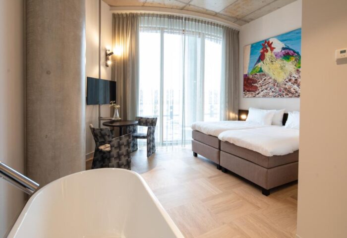 Hotel Pontsteiger gay-friendly room. Twin beds, bathtub, table, and chairs. Modern design, bright with rooster art. Amsterdam hotel for gay men.
