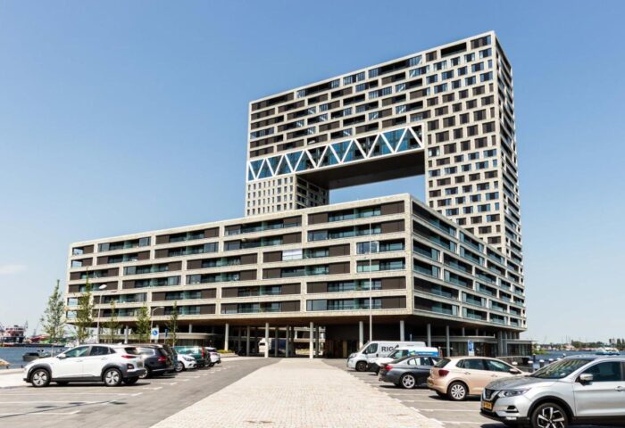Hotel Pontsteiger, a gay-friendly hotel in Amsterdam. Modern architecture with a distinctive hollow center. Parking area in front.