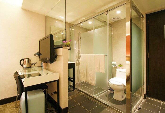 Hotel Puri Ximen's bathroom. Gay-friendly hotel room with glass shower, toilet, desk, and TV. Modern design for gay travelers in Taipei.