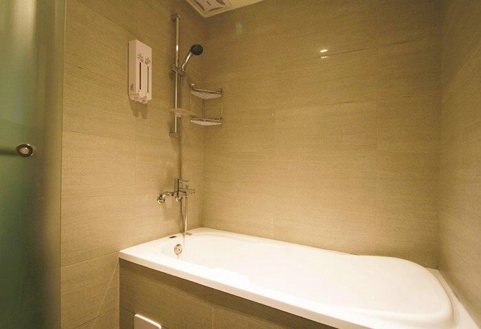 Hotel Puri Ximen bathroom. Bathtub with shower in a gay-friendly hotel. Modern design with neutral tones. Perfect for relaxing after exploring.
