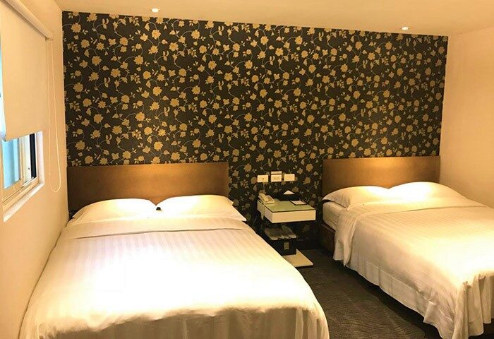 Hotel Puri Ximen gay-friendly room. Two beds with white linens, floral wallpaper, and a modern nightstand. A comfortable stay in Taipei.