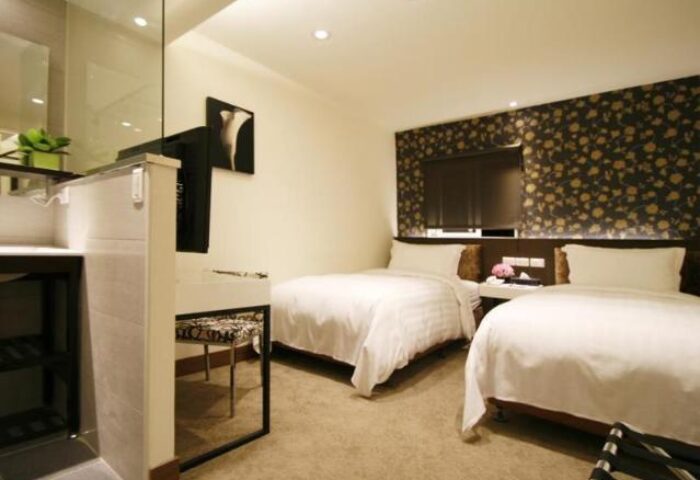 Hotel Puri Ximen's gay-friendly room. Two beds with white linens, floral wallpaper, and a modern sink area. Great for gay travelers.
