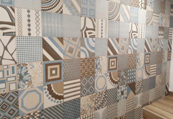 Wall with patterned tiles at Hotel Queens, an adults-only, gay-friendly hotel. Interior design detail in brown, blue, and beige tones.
