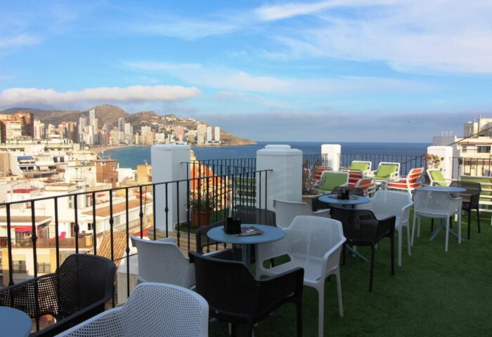 Hotel Queens Adults Only By Mc rooftop terrace view. Gay-friendly hotel with city and ocean views. Tables and chairs on artificial grass.