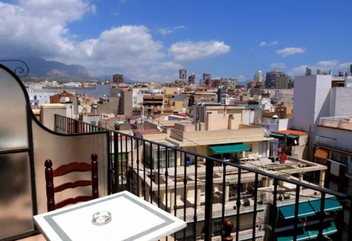 Balcony view from Hotel Queens Adults Only By Mc, a gay-friendly hotel. Table, chair, and city skyline under a blue sky.