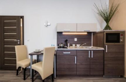 Hotel Residence Spalena gay-friendly room. Kitchenette with microwave, dining table, and chairs. Modern interior for gay travelers.