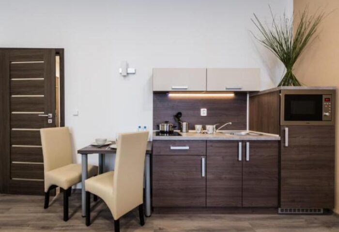Hotel Residence Spalena gay-friendly room. Kitchenette with microwave, dining table, and chairs. Modern interior for gay travelers.